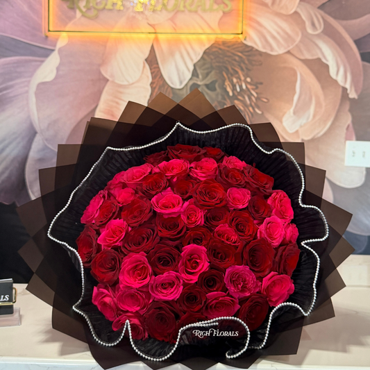 Denaya Bouquet with hot pink and red roses wrapped in black paper with pearl mesh detailing by Rich Florals, Woodbridge NJ